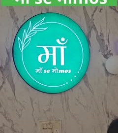 The glowing Ma se Momos sign on a marble wall